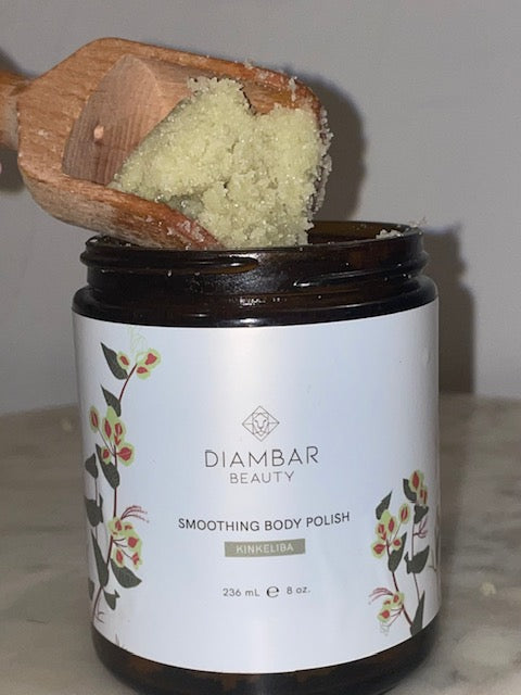 An open jar of Kinkeliba Smoothing Body Polish with a scooper resting on top, filled with the rich, exfoliating scrub.