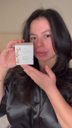 woman holding a beautifully packaged box of Kinkeliba Antioxidant Body Butter, highlighting its elegant design.